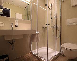 Bagno moderno con lavabo, cabina doccia in vetro e WC sospeso.