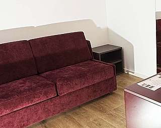 Salotto moderno con divano-letto, tavolino e specchio a parete.